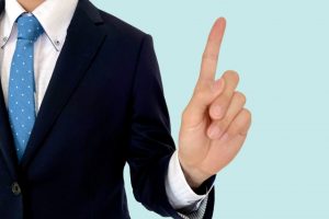 スーツ姿で人差し指を立てる男性の画像