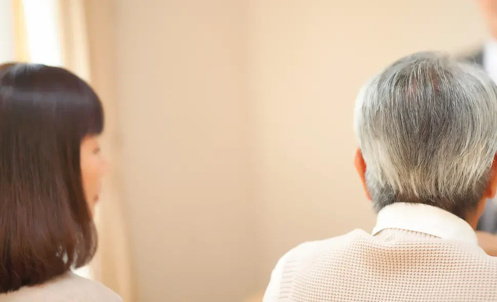 親の葬儀費用について話し合う中年の兄弟のイメージ画像