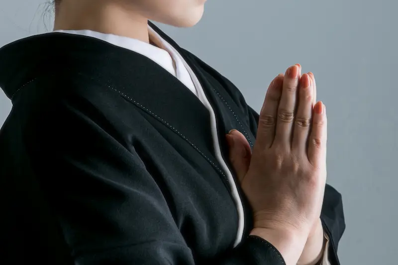 通夜で合掌する女性の画像